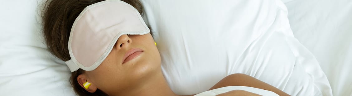 Woman wearing eye mask and using earplugs