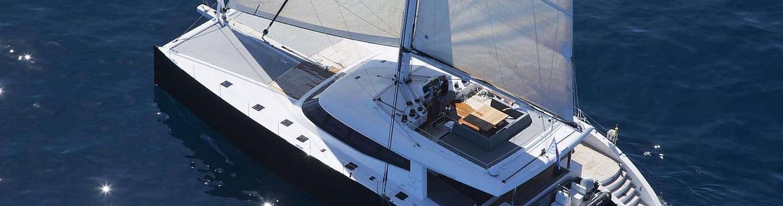 Luxurious sailing catamaran cruising in open ocean waters, featuring expansive deck space and modern sails.