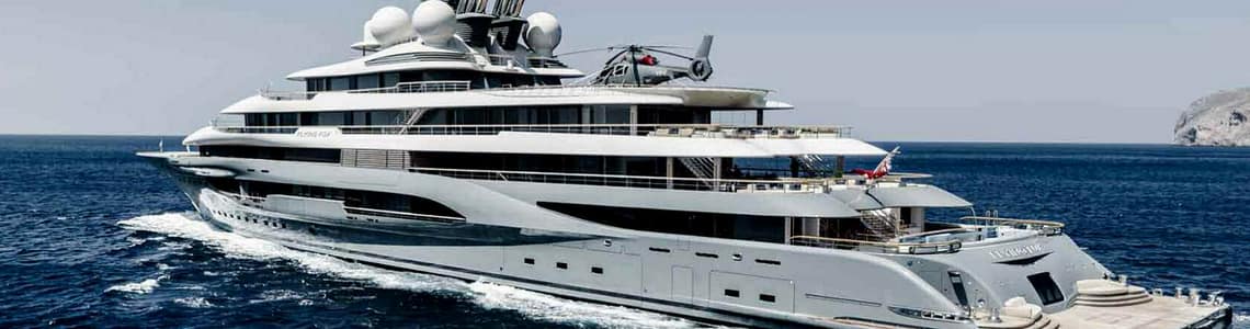 Luxury yacht cruising on the ocean with a helicopter on deck, showcasing modern design and opulence.