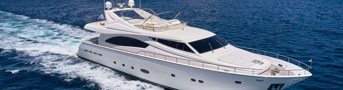 Luxury white yacht sailing on clear blue ocean near rocky coastline, showcasing sleek design and spacious deck.