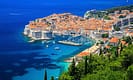 Aerial view of Dubrovnik, Croatia, showcasing the historic Old Town with its iconic red rooftops, medieval walls, and the surrounding blue Adriatic Sea.