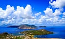 Scenic view of Lipari Island in Italy with lush green terrain, clear blue sea, and vibrant sky with fluffy clouds.