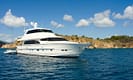 Luxury yacht anchored near a scenic coastline under a clear blue sky.