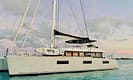 Catamaran yacht on calm ocean water at sunset with paddleboards, featuring a sleek design and modern sails.