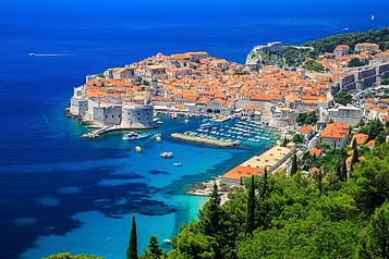 Aerial view of Dubrovnik, Croatia, showcasing the historic Old Town with its iconic red rooftops, medieval walls, and the surrounding blue Adriatic Sea.