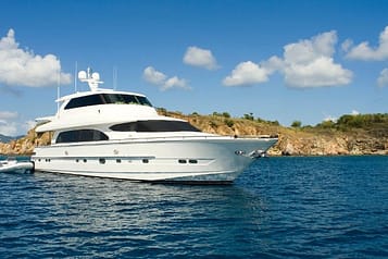 Luxury yacht anchored near a scenic coastline under a clear blue sky.