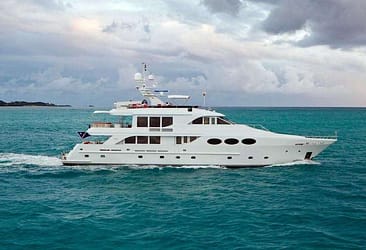Luxury yacht sailing on turquoise ocean waters under a cloudy sky, showcasing elegant design and premium maritime leisure.