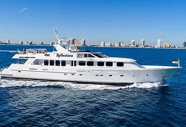 Luxury yacht on clear blue ocean, city skyline in the background, perfect for travel and leisure.