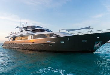 Luxury yacht sailing on clear blue waters at sunset, showcasing sleek design and modern features against a scenic ocean backdrop.