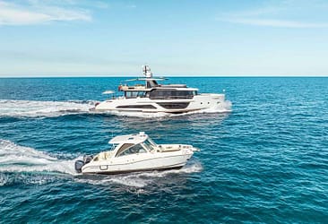 Luxury yacht and motorboat cruising on open sea under clear blue sky.