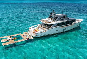 Luxury yacht anchored in clear turquoise waters with floating docks and water sports equipment.