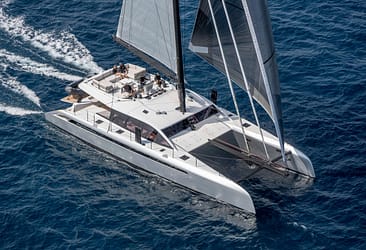 Luxury catamaran sailing on open blue ocean with passengers enjoying a sunny day