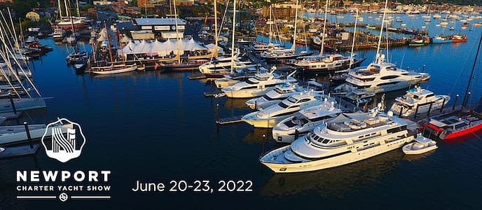 Aerial view of luxury yachts docked at Newport Charter Yacht Show, June 20-23, 2022, showcasing a harbor filled with boats and an event tent.