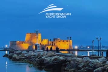 Night view of a historic fortress illuminated along a rocky shoreline during the Mediterranean Yacht Show showcasing vibrant coastal scenery and maritime heritage.