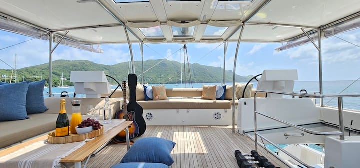 Luxury yacht deck with comfortable seating, ocean view, champagne, grapes, and a guitar, ideal for relaxation and leisure.