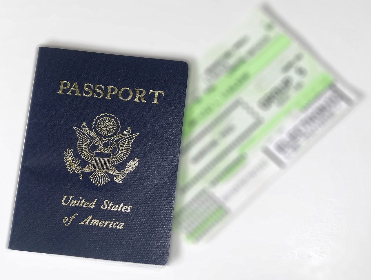 USA passport next to a blurred airline ticket on a white background.