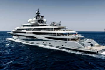 Luxurious superyacht with helicopter cruising on open sea with blue water and clear sky in the background