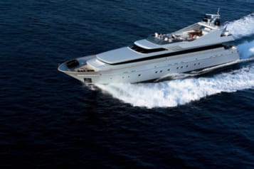 Luxury yacht cruising on the open sea with passengers enjoying the sun on deck.