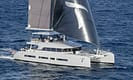 Luxury sailing catamaran with modern design and large sails navigating the open ocean, showcasing advanced nautical engineering and high-end yachting features.